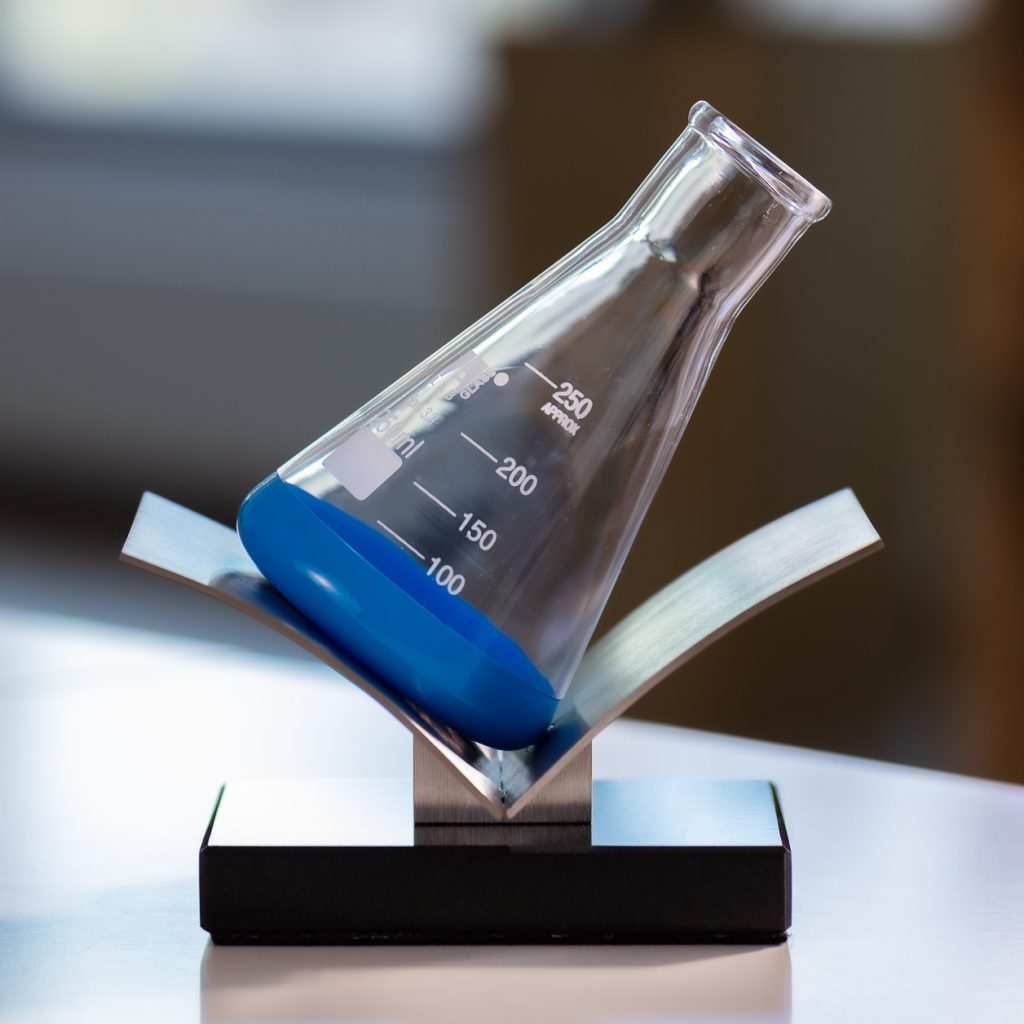 Metal pedestal with stone base. Glass bottle sandblasted, painted and baked.